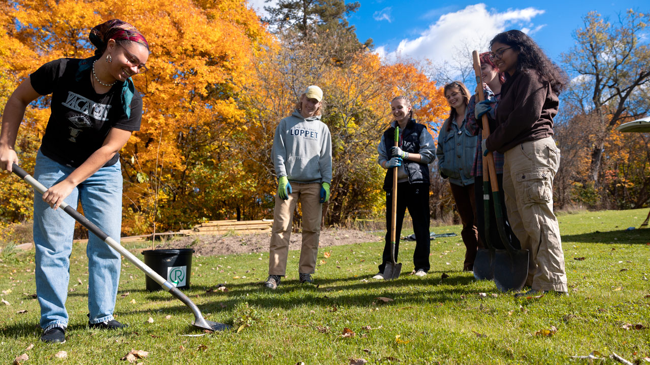 students look on as peer uses shovel