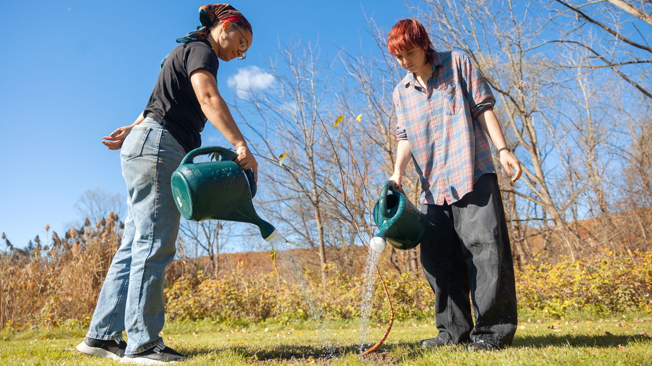 two students using watering can in garden