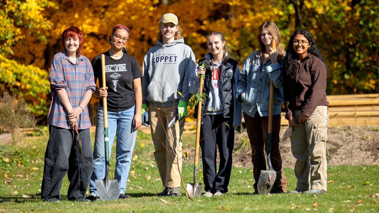 five students pose for picture with gardening gear